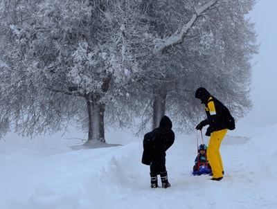 男人黑夹克和黄色的裤子站在冰雪覆盖的地面白天
